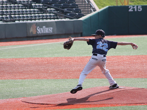 Jeffrey at 11 in baseball uniform pitching on a baseball field's pitcher mound