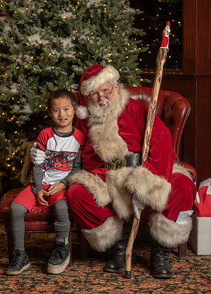 Primo wearing a shoe lift sitting with Santa Claus