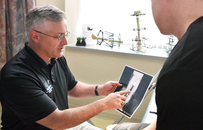Dr. Shawn Standard talking to an International Center for Limb Lengthening patient while showing him an x-ray of his legs