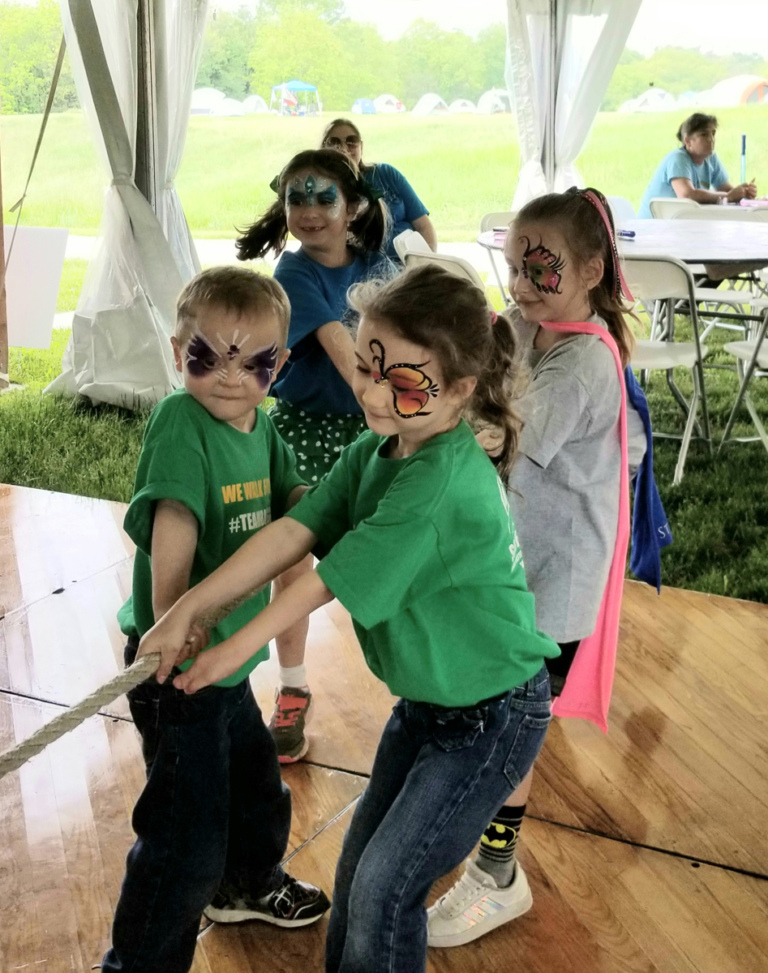 One tug of war team with children straining holding the rope