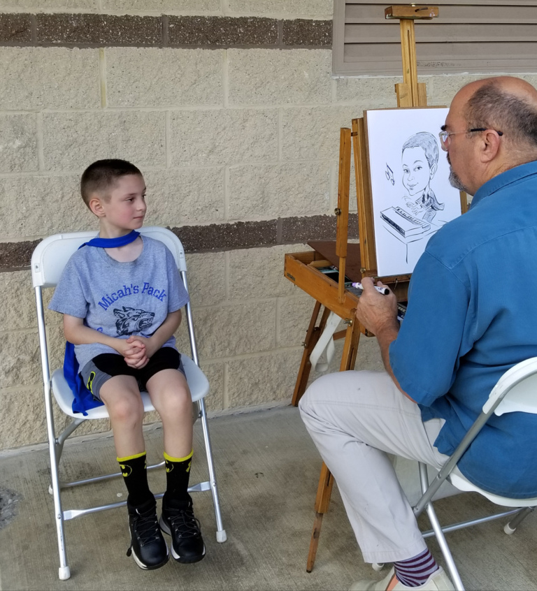 A young patient sitting while an artist draws his caricature