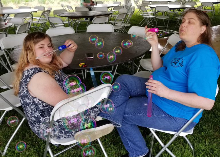 A young patient and her mother sitting blowing bubbles