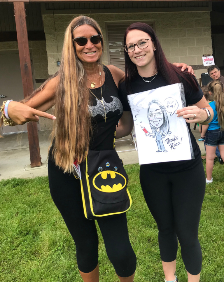 Pediatric Liaison Marilyn Richardson with a woman who is a former patient pointing to the patient’s caricature depicting herself in her current job as a nurse