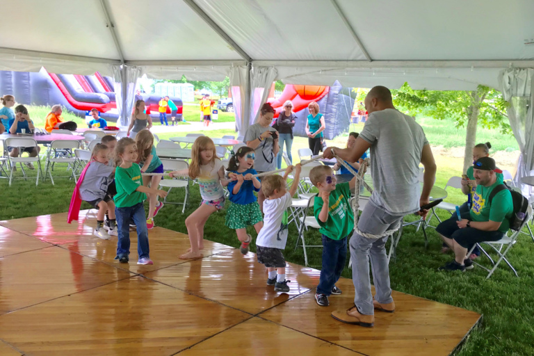 A group of children playing tug of war with the DJ at the Camp Save-A-Limb Festival