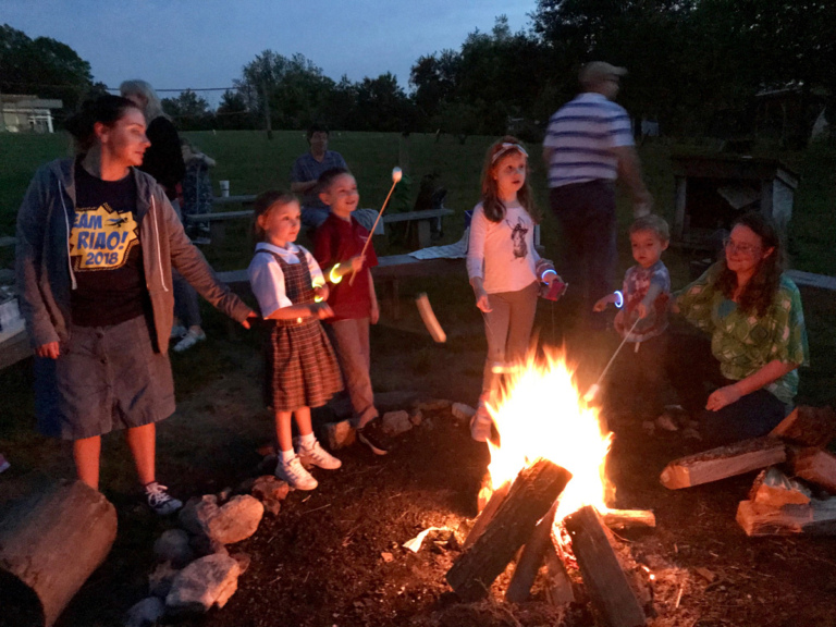 Camp Save-A-Limb participants roasting marshmallows around a campfire
