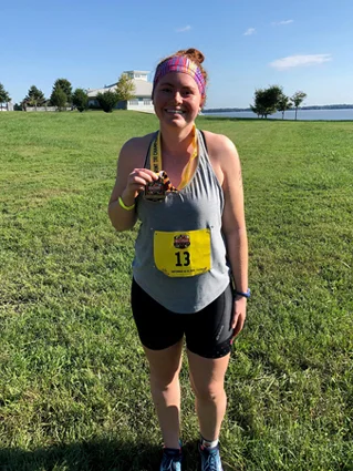 Carly holding up a medal after a race