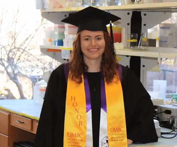Carly in her graduation cap and gown in a science lab
