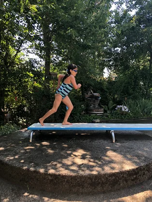 Gracie running on a diving board at a swimming pool 9 months after surgery no longer needing a leg brace
