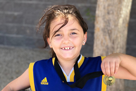 Gracie holding a basketball and a medal after she was cleared to play basketball again