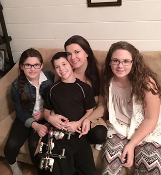 Jackson wearing an external fixator sitting with his mom and sisters