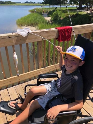 Preston with a fish he caught from his wheelchair by a lake