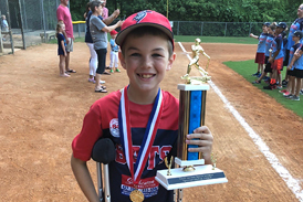 Preston on crutches on a baseball field with a medal and trophy