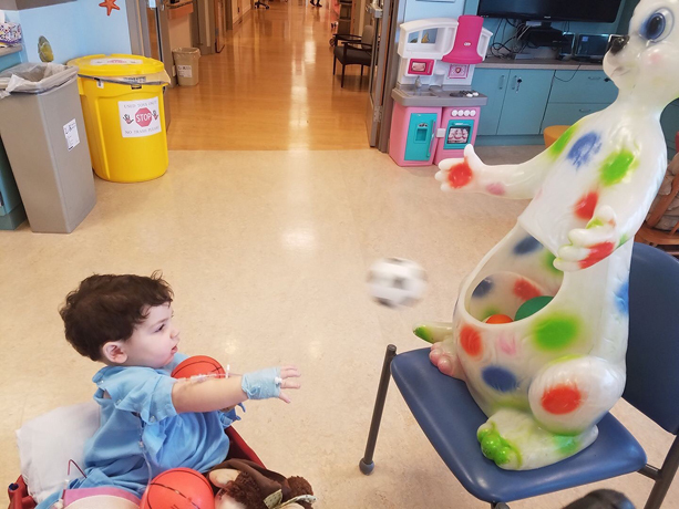 Ross playing a ball toss game while sitting in a wagon at the Herman & Walter Samuelson Children's Hospital