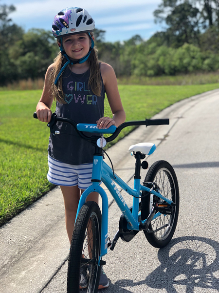 Emma in a Girl Power t-shirt and helmet with a bicycle