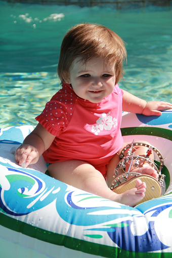 Emma as a toddler wearing an external fixator on one leg in a float in a pool