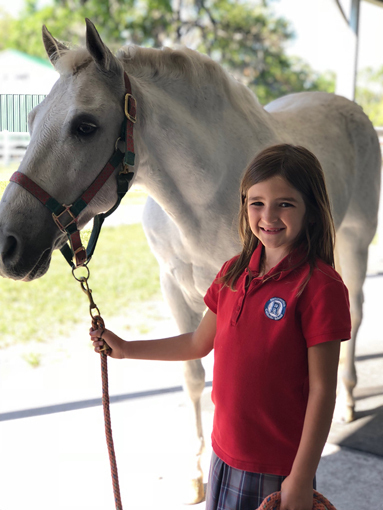 Emma leading a white horse