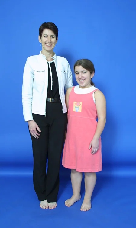Hannah in her early teens standing next to her mother before her lengthening surgery; she is shorter than her mother's shoulders.
