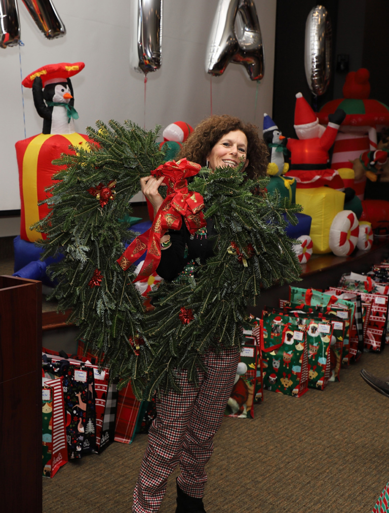 Smiling volunteer carrying a giant heart-shaped pine wreath