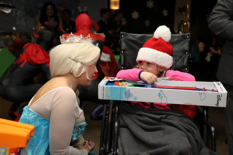 Young girl in wheelchair with a toy talking with a Disney Princess