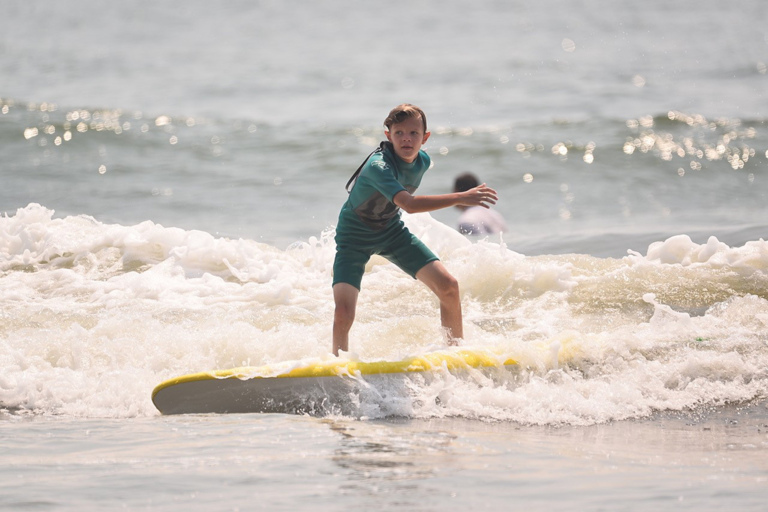 Jeffrey at 10 surfing on a surf board in the ocean