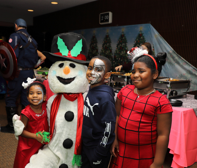 2 young girls and a boy smiling with Frosty the Snowman