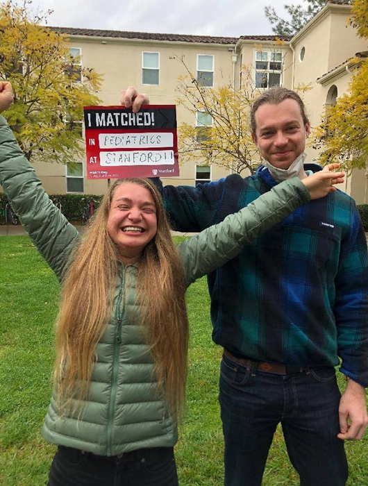 Maïté smiling with a sign saying she matched to start her pediatrics residency at Stanford University Medical Center.