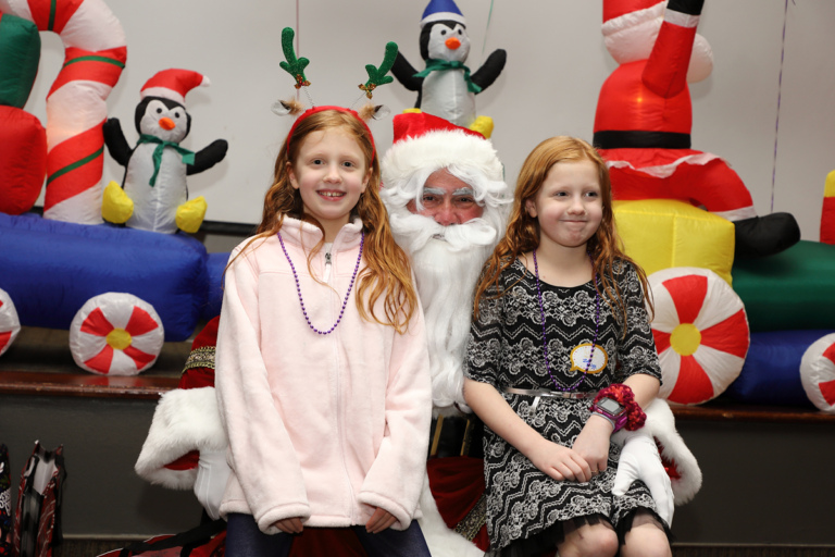 Two girls smiling on Santa’s lap