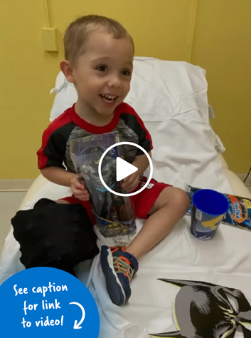 A little boy sitting in a hospital bed and holding a Batman toy