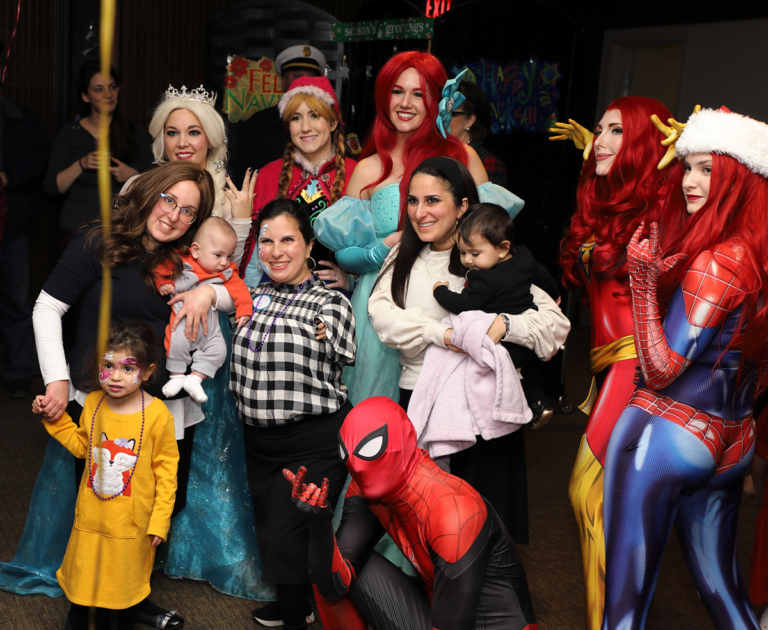 Family of three women and three young children smiling with Disney Princesses and comic book superhero and villainess