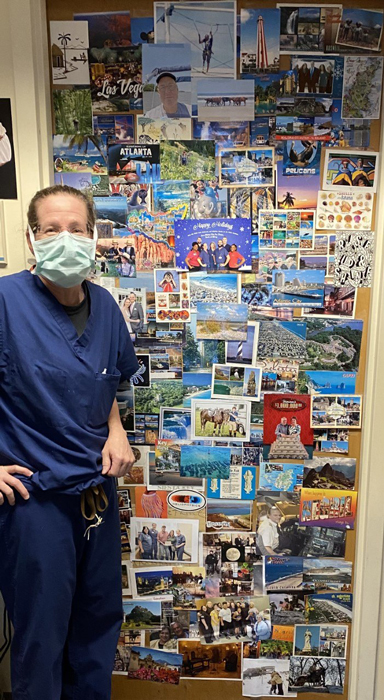 Dr. Janet Conway standing in front of her office door with postcards from patients attached to it