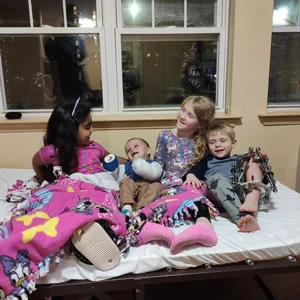 Four children with external fixators on their legs sitting on a bed at the Hackerman-Patz House