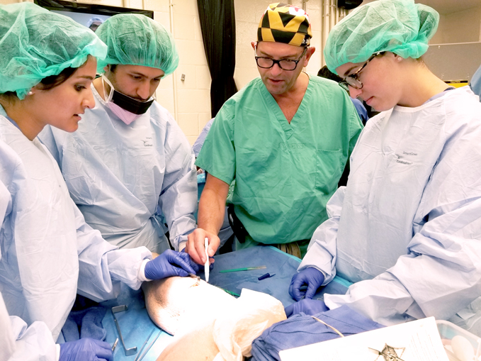 Dr. Christopher Bibbo teaching students how to perform a procedure during a cadaver lab