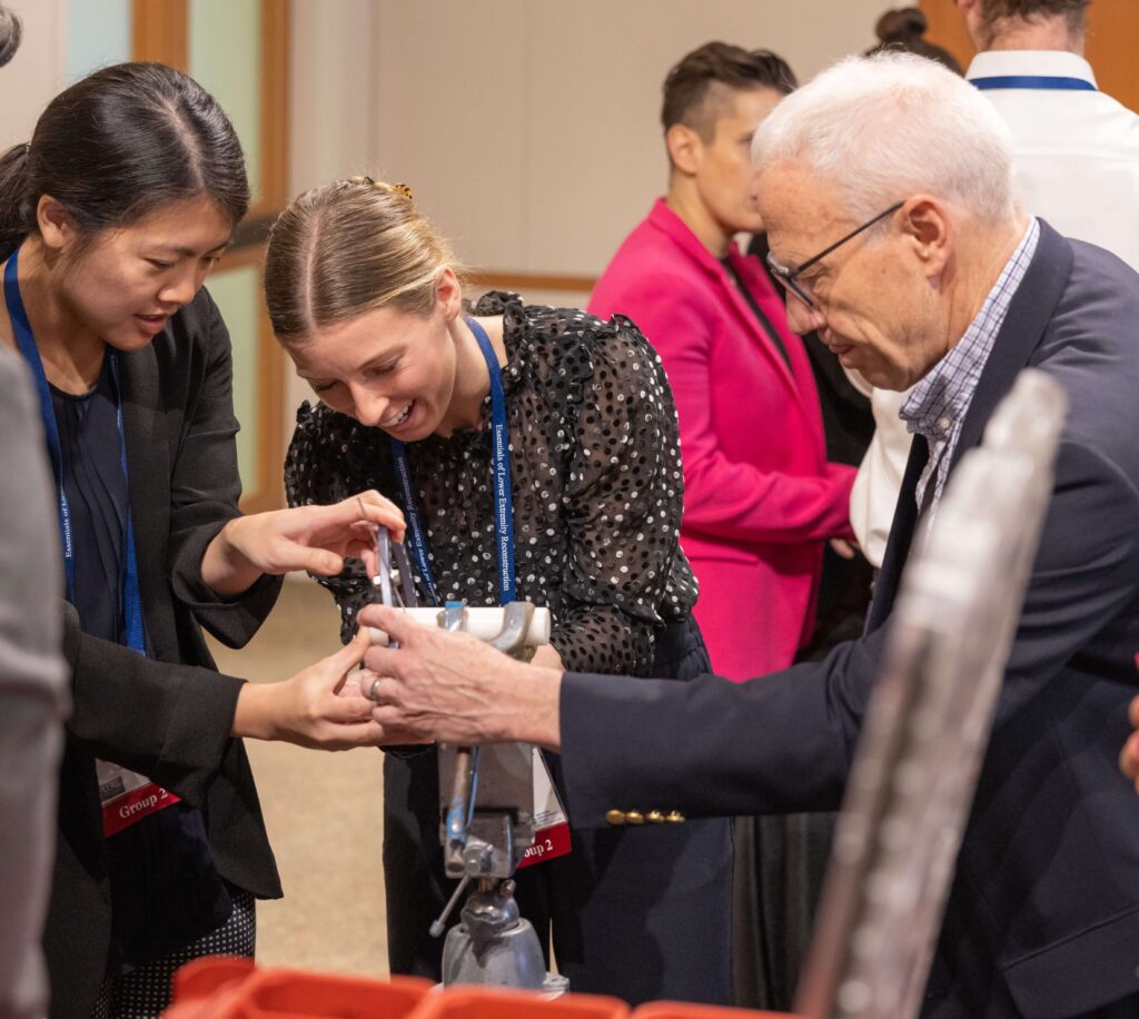 Two participants working with an instructor in the hands-on sawbone lab