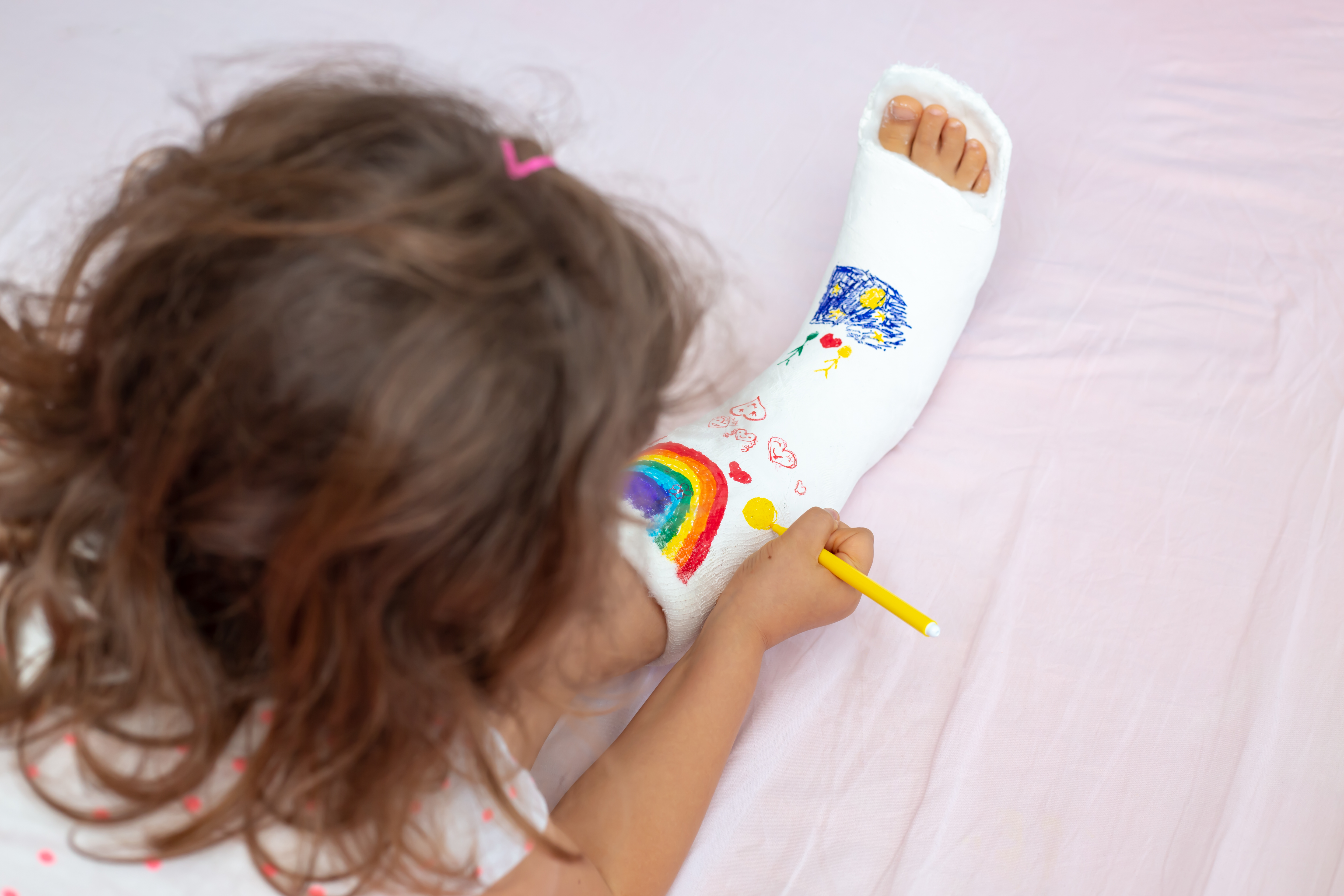 young girl coloring a cast on her leg