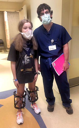 Bridget standing wearing external fixators on both legs by Dr. McClure