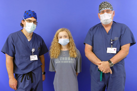 Bridget with straightened legs after treatment standing between Dr. McClure and Dr. Herzenberg