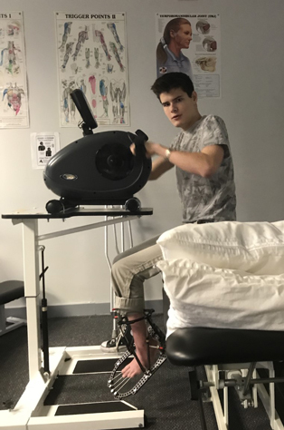 Jack in a hospital room with an external fixator on his leg using a physical therapy device