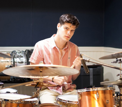 Jack holding drumsticks while sitting at a drum set