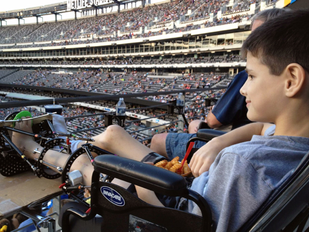 Jack sitting in a wheelchair with an external fixator on his leg at a baseball game