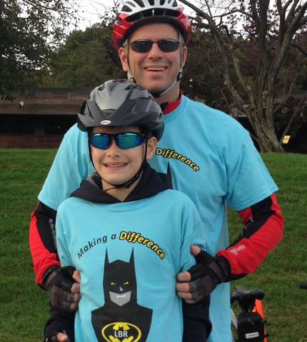 Jack and his dad smiling and wearing bike helmets at the Save-A-Limb Ride