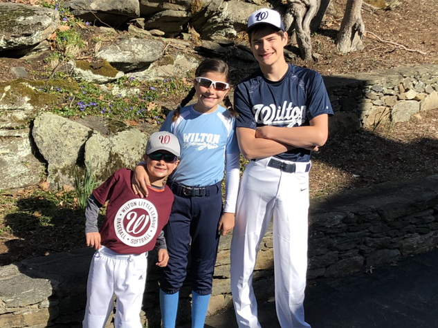Jack together with his brother and sister wearing baseball uniforms and smiling