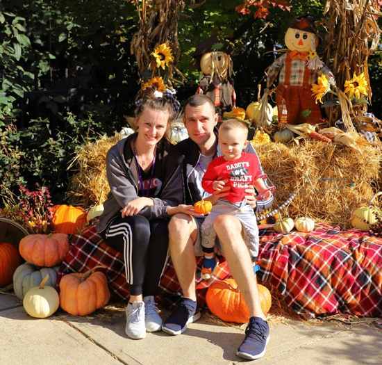 Kacper with his mother and father posing for a picture next to an autumn display