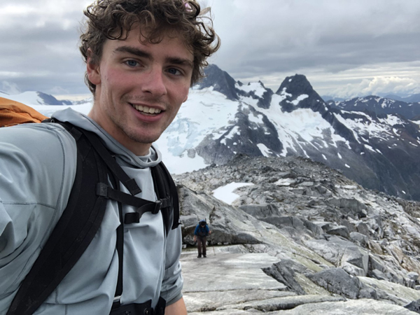 Keagan smiling with snowy mountain tops in the background