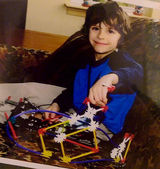 Keagan smiling with an external fixator on his leg while sitting on a couch