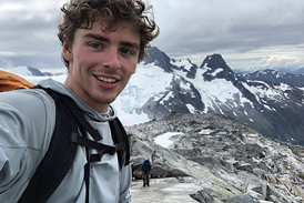 Keagan smiling with snowy mountain tops in the background