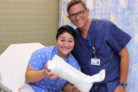 Dr. Christopher Bibbo smiling with Lili while she holds her cast
