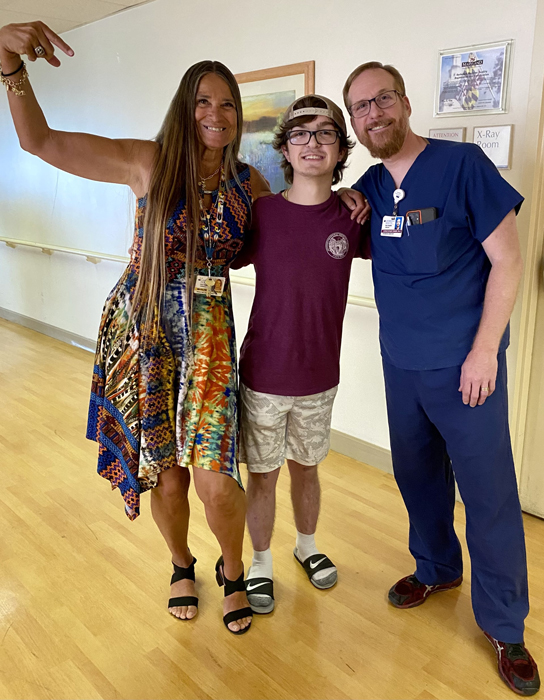 Preston standing smiling with Pediatric Liaison Marilyn Richardson and Physician Assistant Chris Fisher at his treatment completion