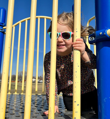 Riley sitting on a jungle gym