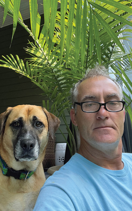 Steve with his dog next to a potted plant