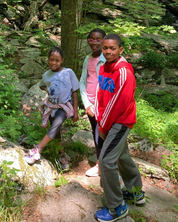 Sudan and two girls smiling while out in nature for a hike